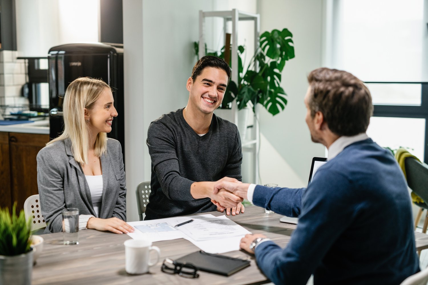 happy couple shaking hands with their real estate agent at home.